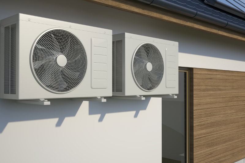 air conditioners sitting on the outside of a wall.