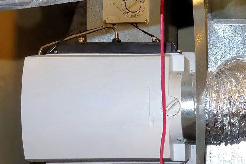 An HVAC system component, likely a whole-house bypass humidifier, installed on ductwork
